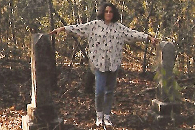 A photo of Ariel Emmerson standing by the graves of slaves on the property of her ancestors.